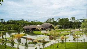 Un complexe hôtelier doté de bâtiments à toits de chaume, situé au bord d’un lac et entouré d’une végétation luxuriante.