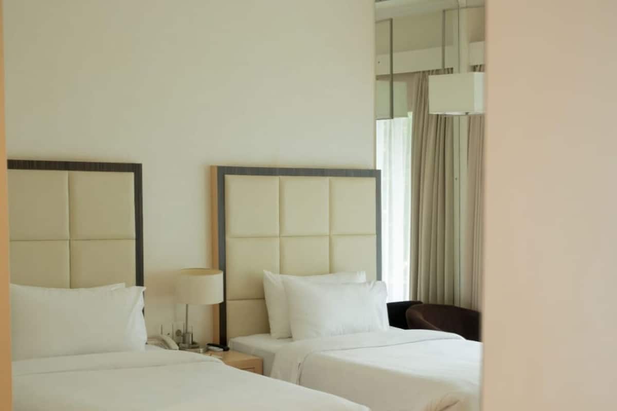 A hotel room with two beds, a mirror, and a table with toiletries.