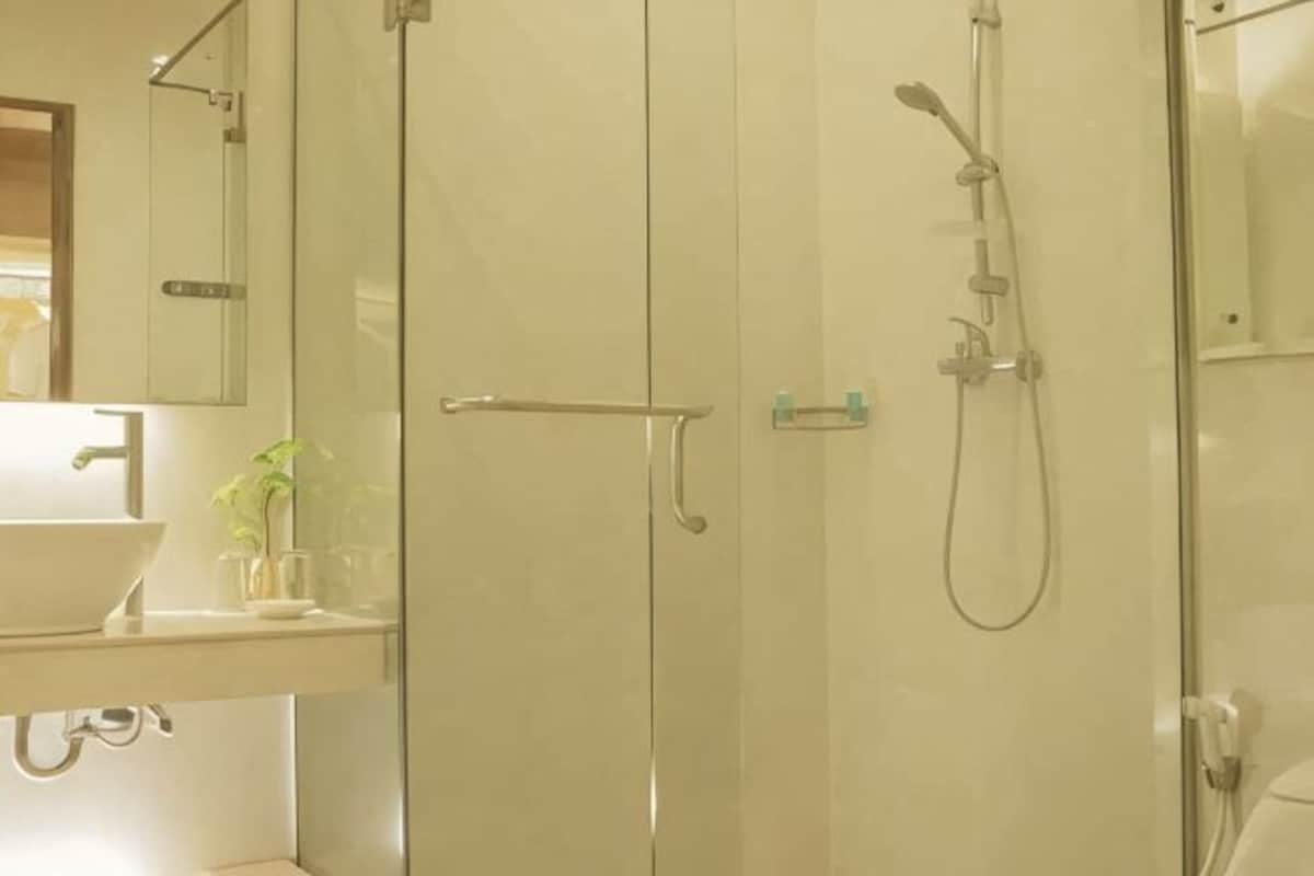 Un baño con cabina de ducha de vidrio, lavamanos y espejo.