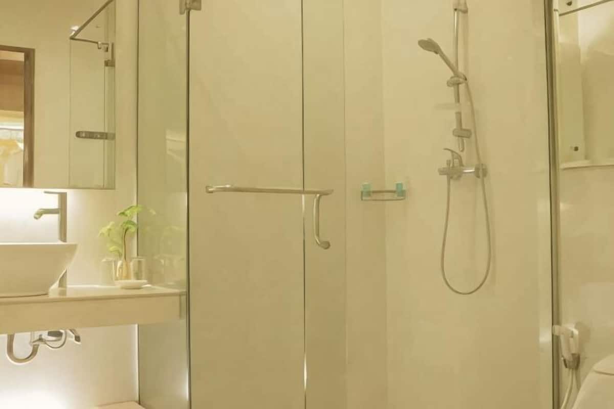 A bathroom with a glass shower enclosure, a sink, and a mirror.