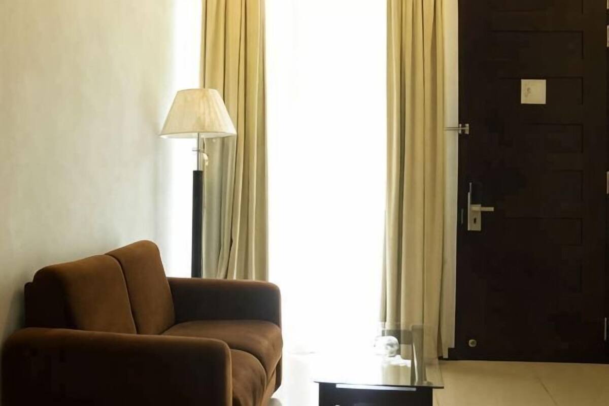A room with a sofa, a lamp, and a door.