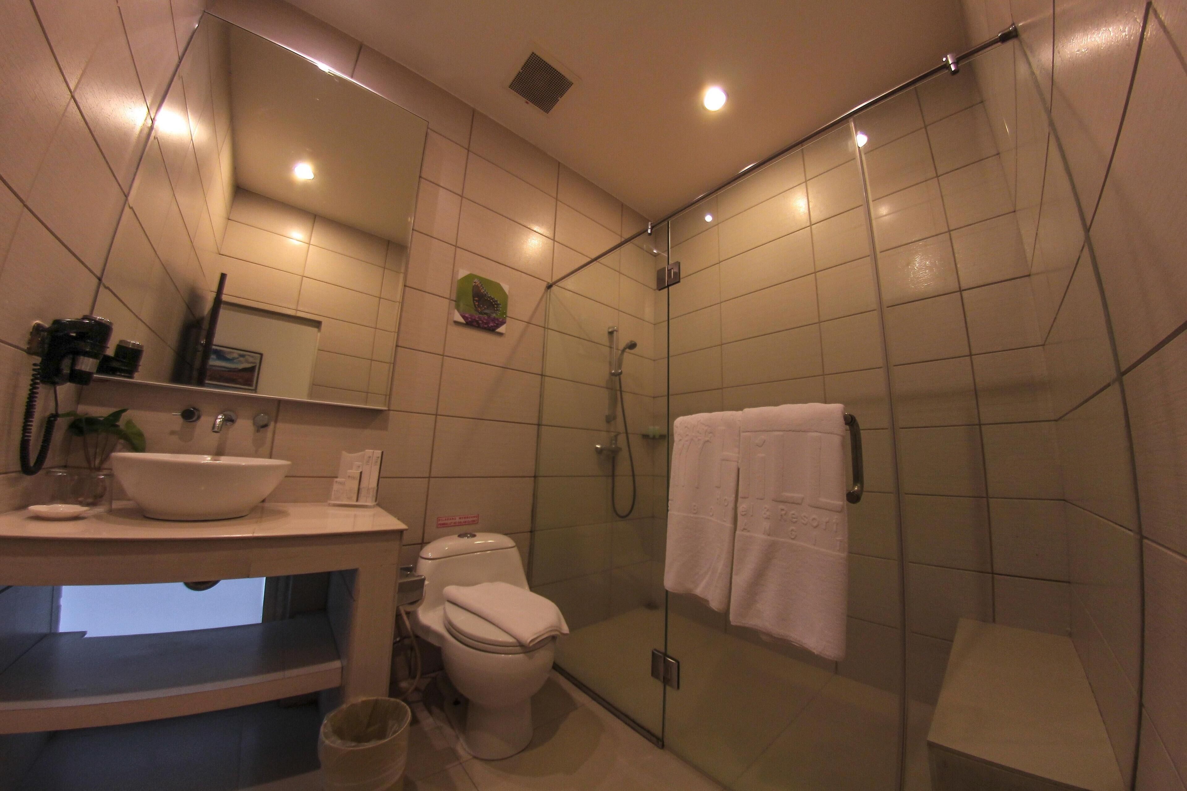 Un baño moderno con ducha acristalada, inodoro y lavamanos con espejo.