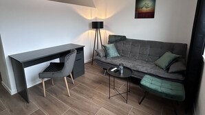 Une chambre moderne équipée d’un bureau, d’une chaise, d’un canapé et d’un lampadaire.