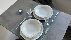 Une table à manger dressée avec des assiettes, des couverts et un verre.