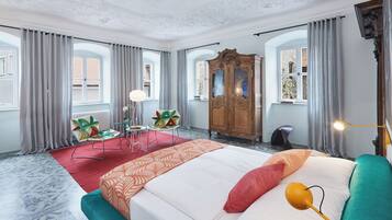A spacious bedroom with a large bed, a wooden wardrobe, and a red carpet.