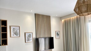 Un soggiorno moderno con una televisione a schermo piatto montata su un pannello di legno, un divano grigio e un tavolo da pranzo.