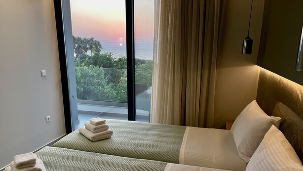 Una camera d'albergo con un letto, vista sull'oceano e un balcone.