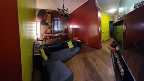 Ein Wohnzimmer mit einer Couch, einem Esstisch und einem Fernseher.