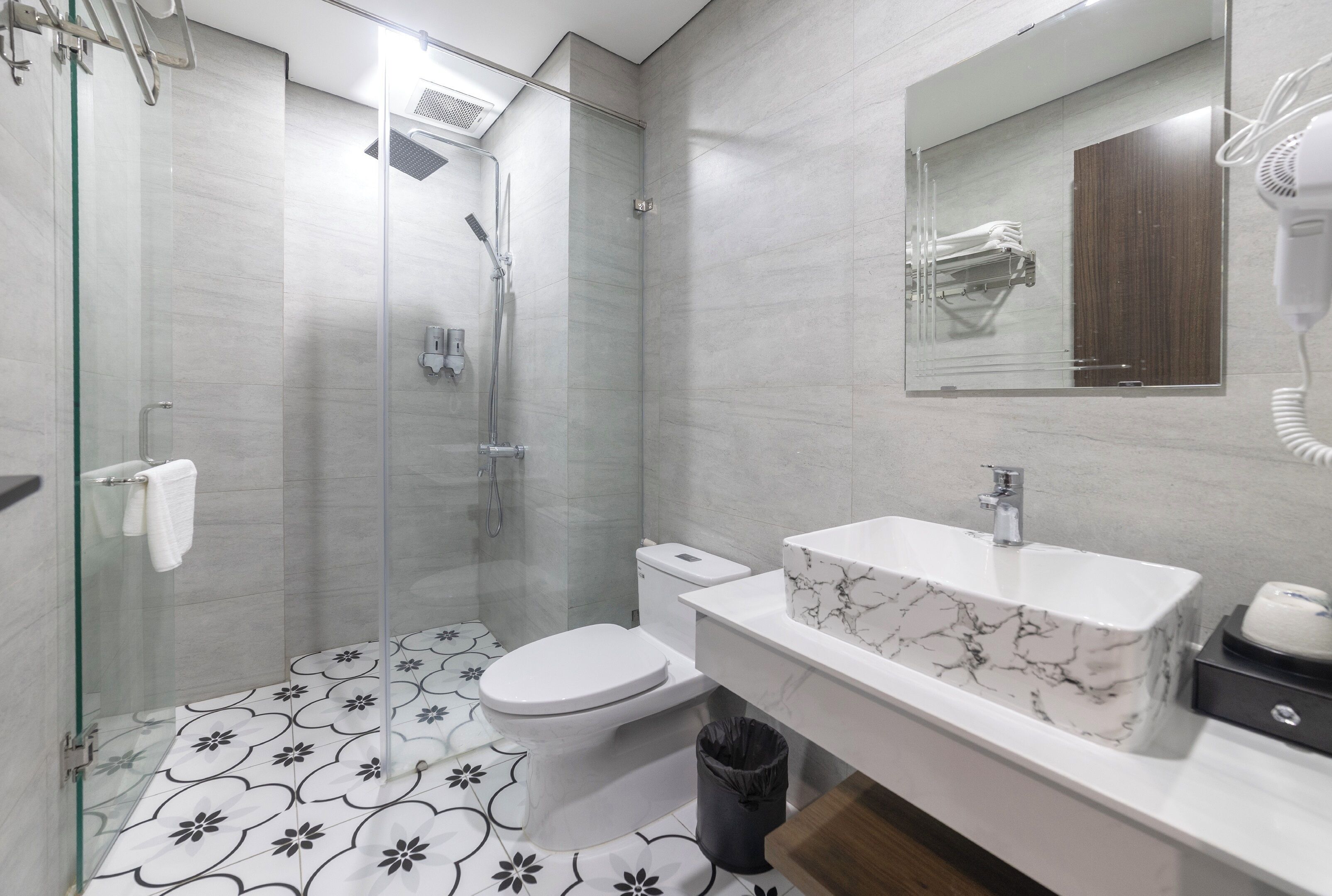 A modern bathroom with a glass-enclosed shower, a white toilet, and a marble sink.