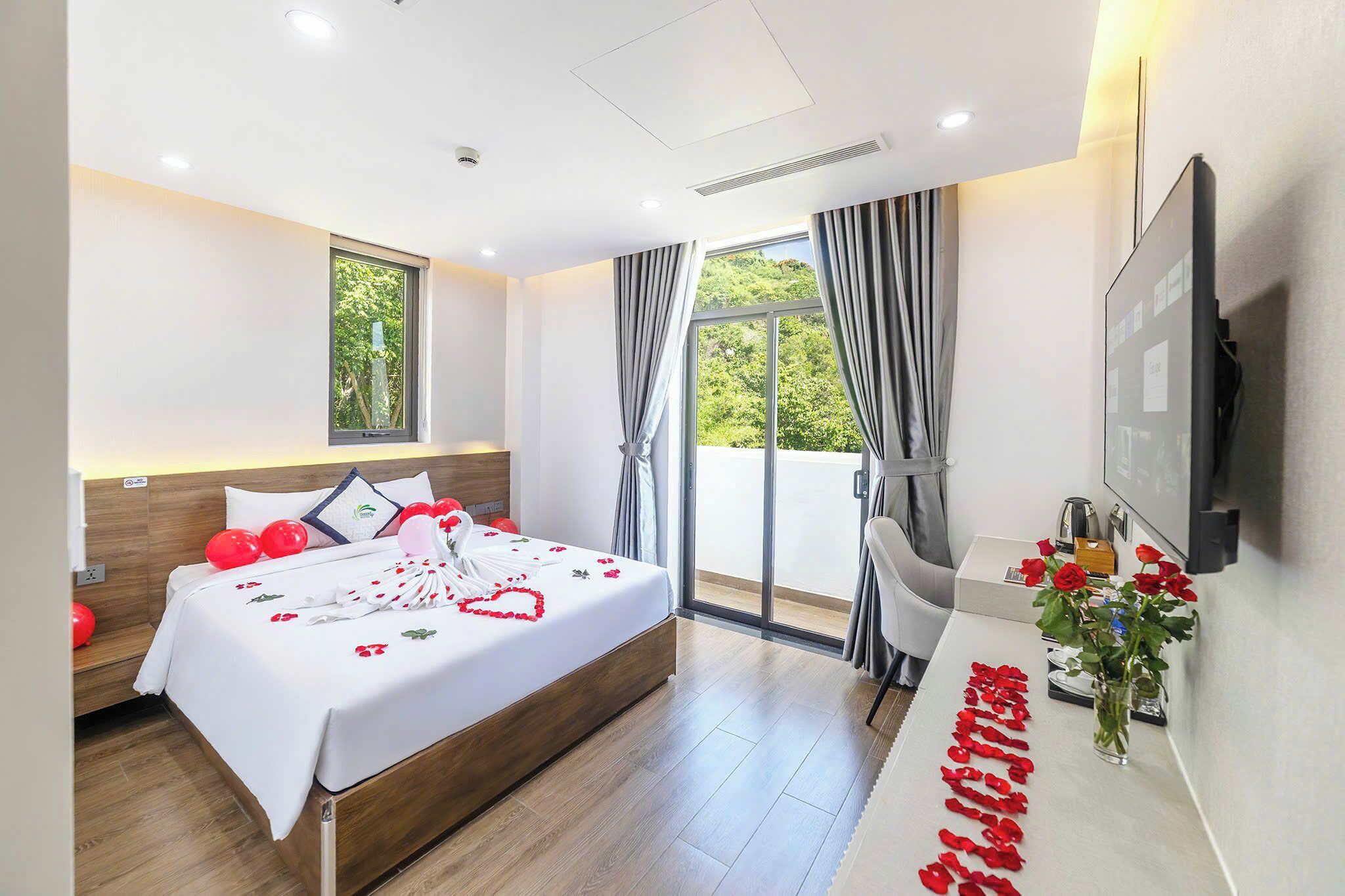 A hotel room with a bed, a desk, a TV, and a window with curtains.