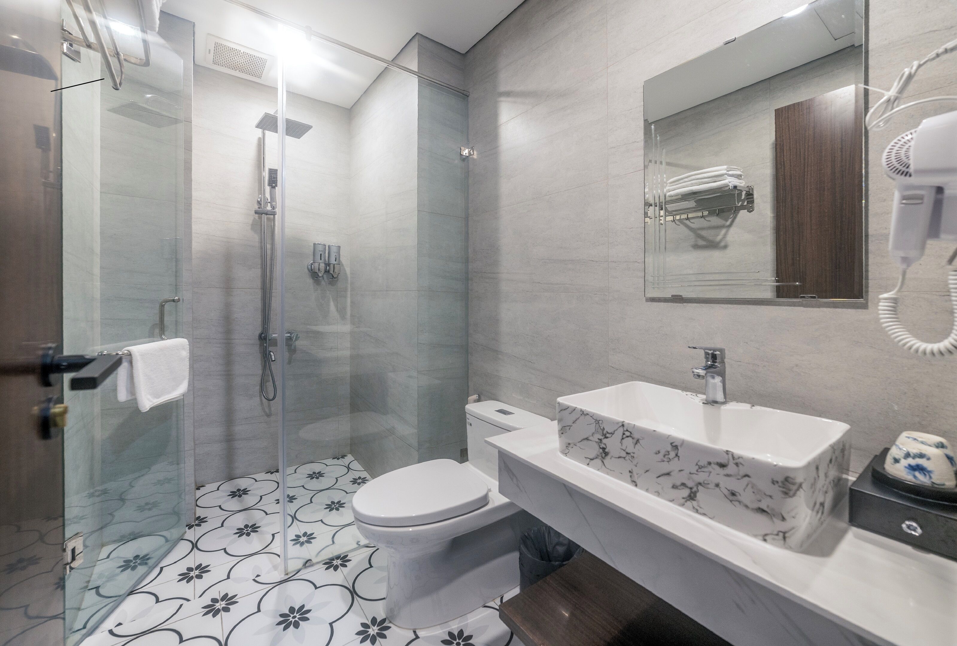 A modern bathroom with a glass-enclosed shower, a toilet, and a vanity with a marble sink.