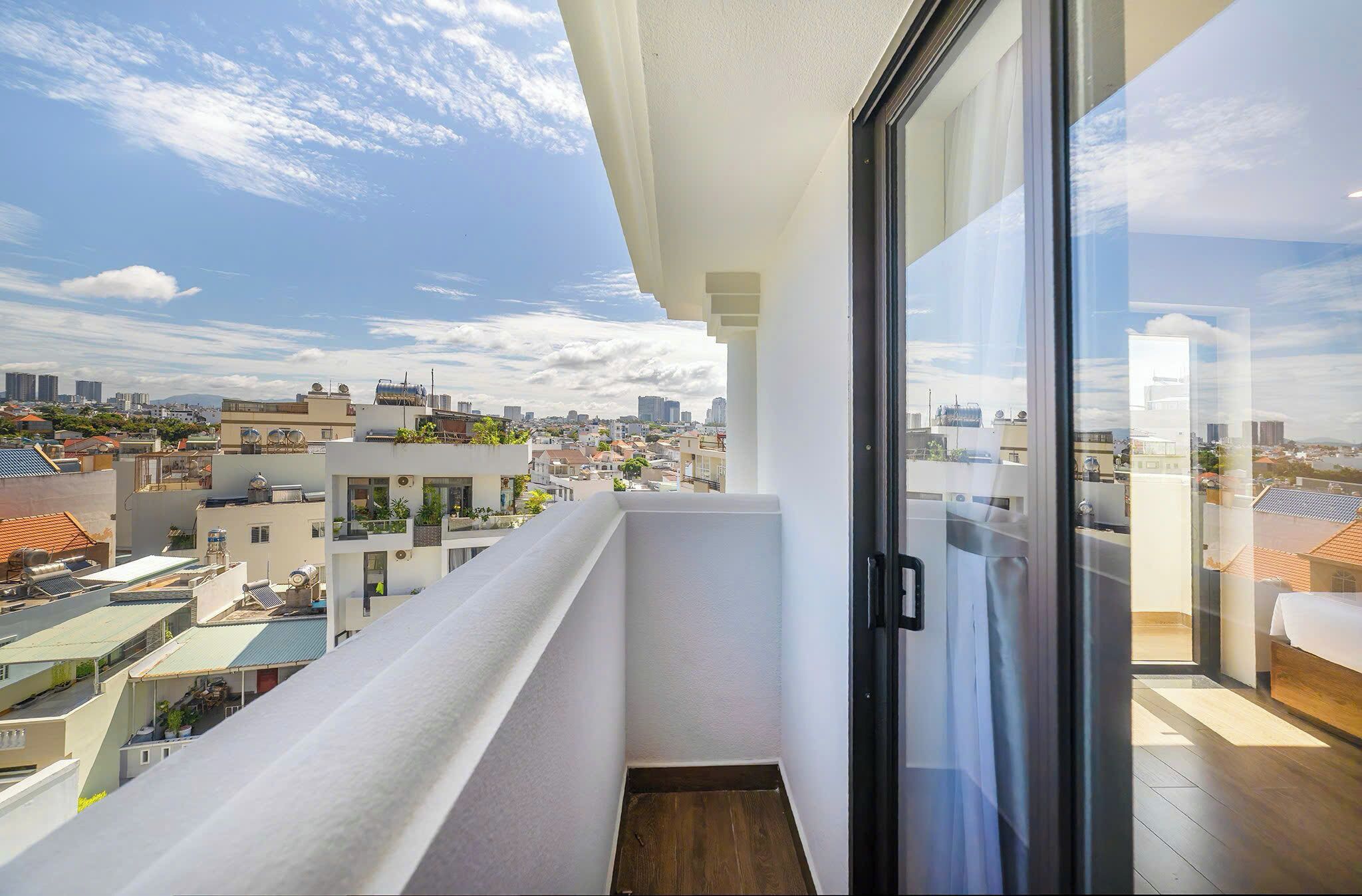 Un balcón con vista a la ciudad, una puerta de vidrio y suelo de madera.