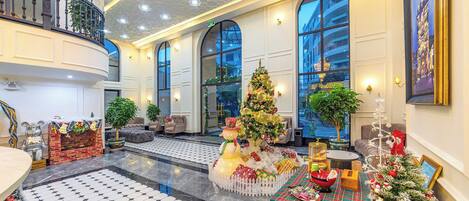 A spacious lobby with a high ceiling, large windows, and a central Christmas tree.