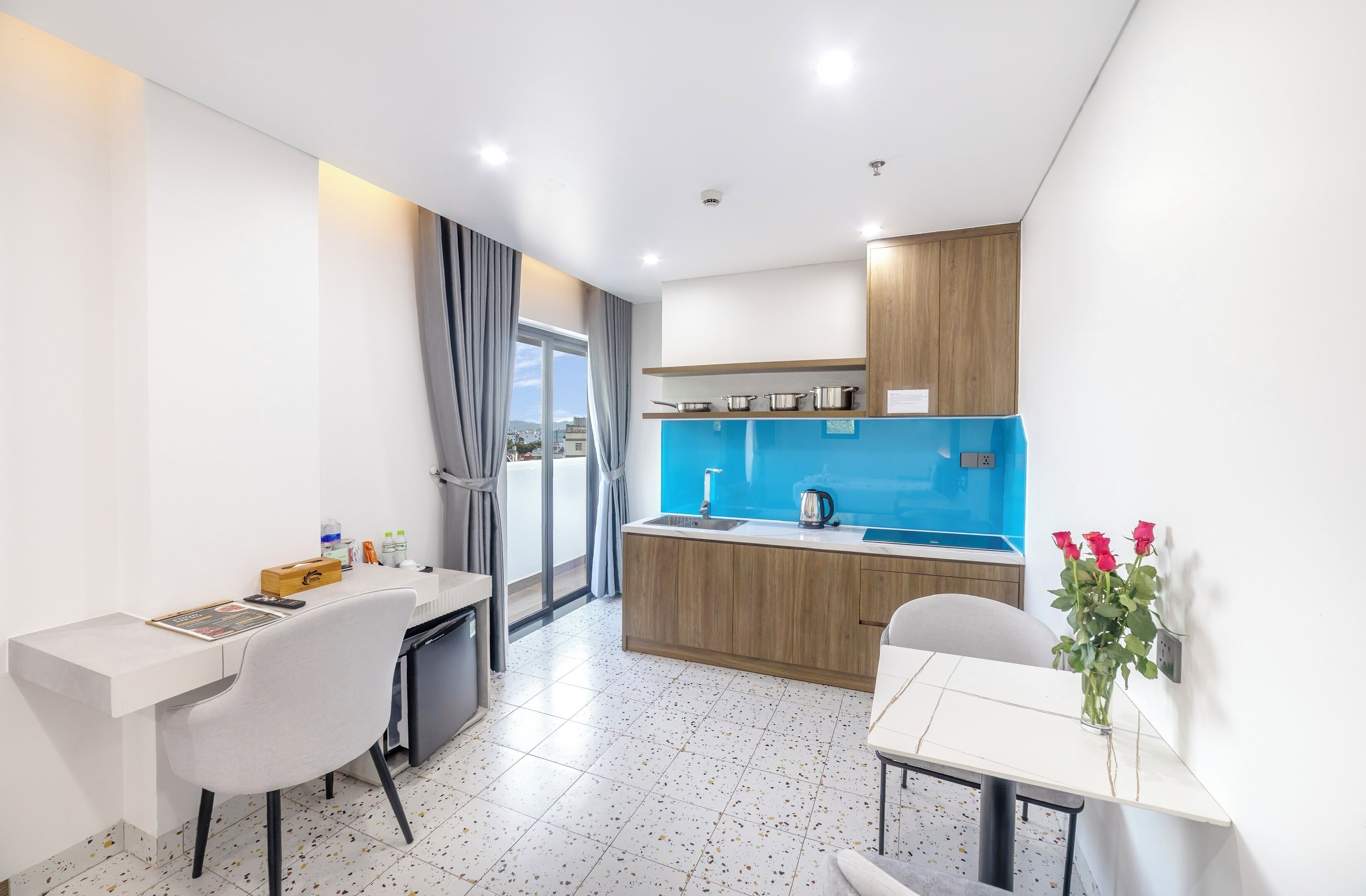 A modern kitchen with a blue backsplash, wooden cabinets, and a dining area with a white table and chairs.