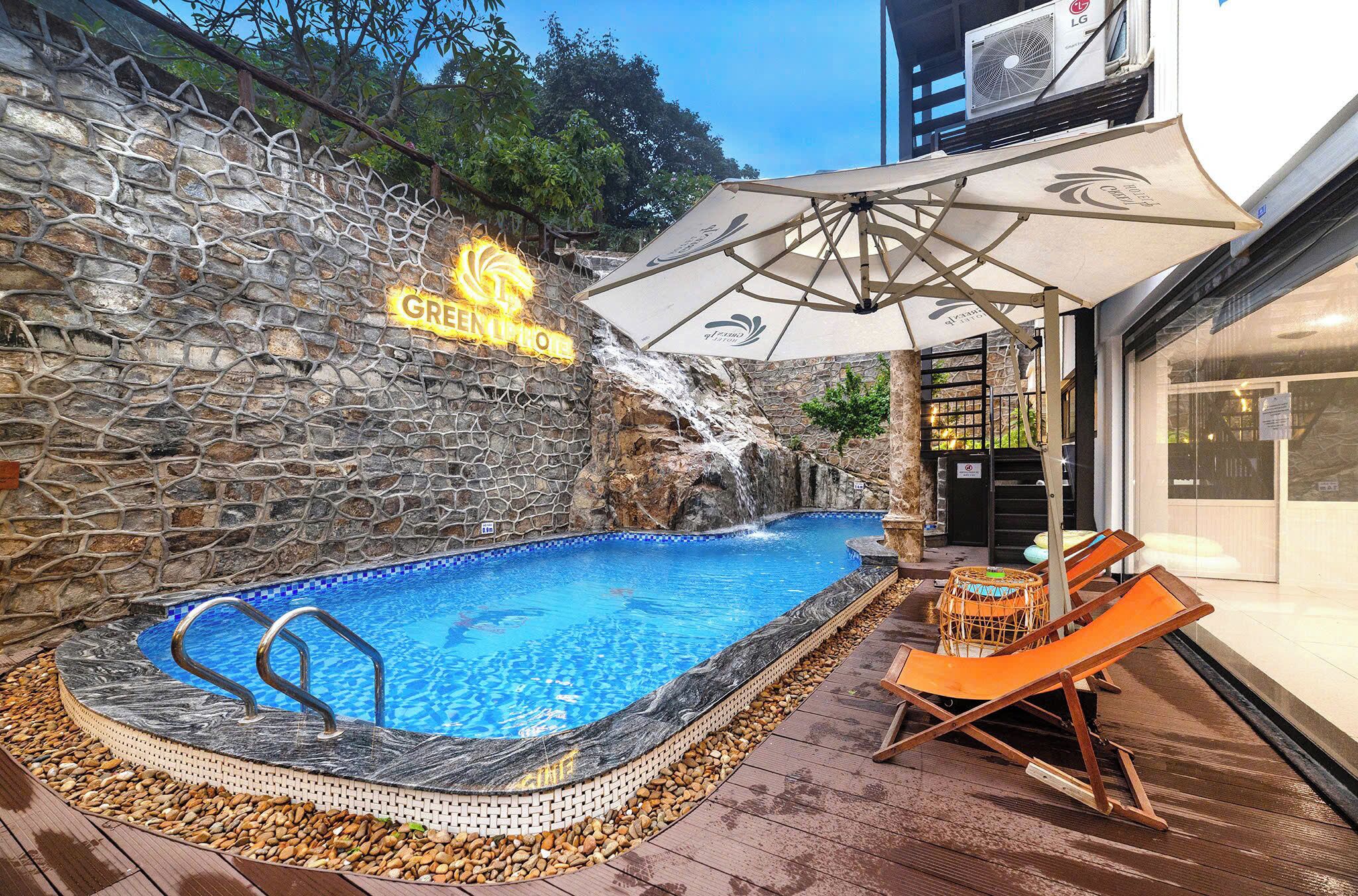 Une piscine avec un mur en pierre, une cascade et des chaises longues.