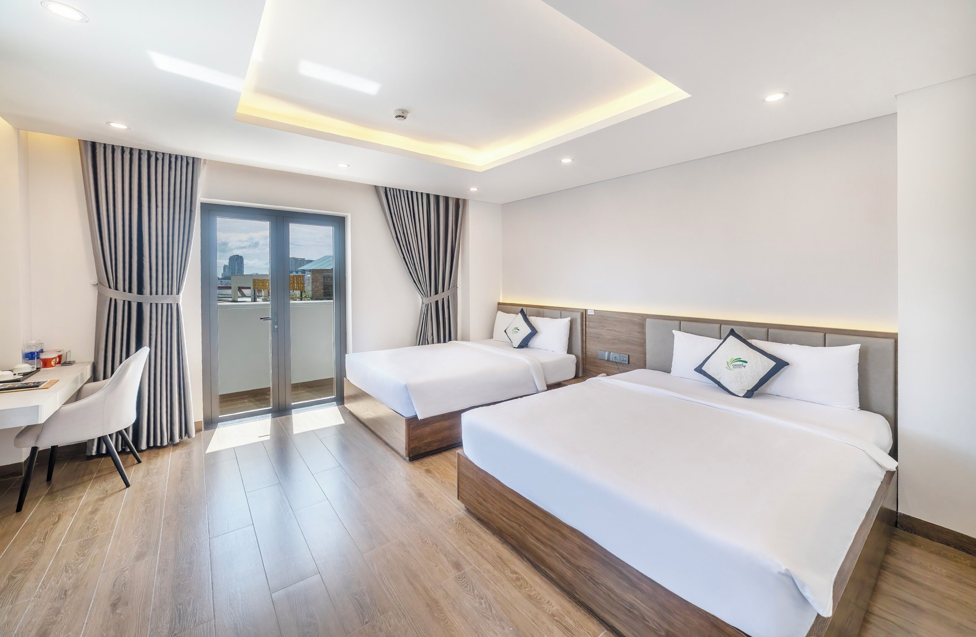 A hotel room with two beds, a desk, and a chair.