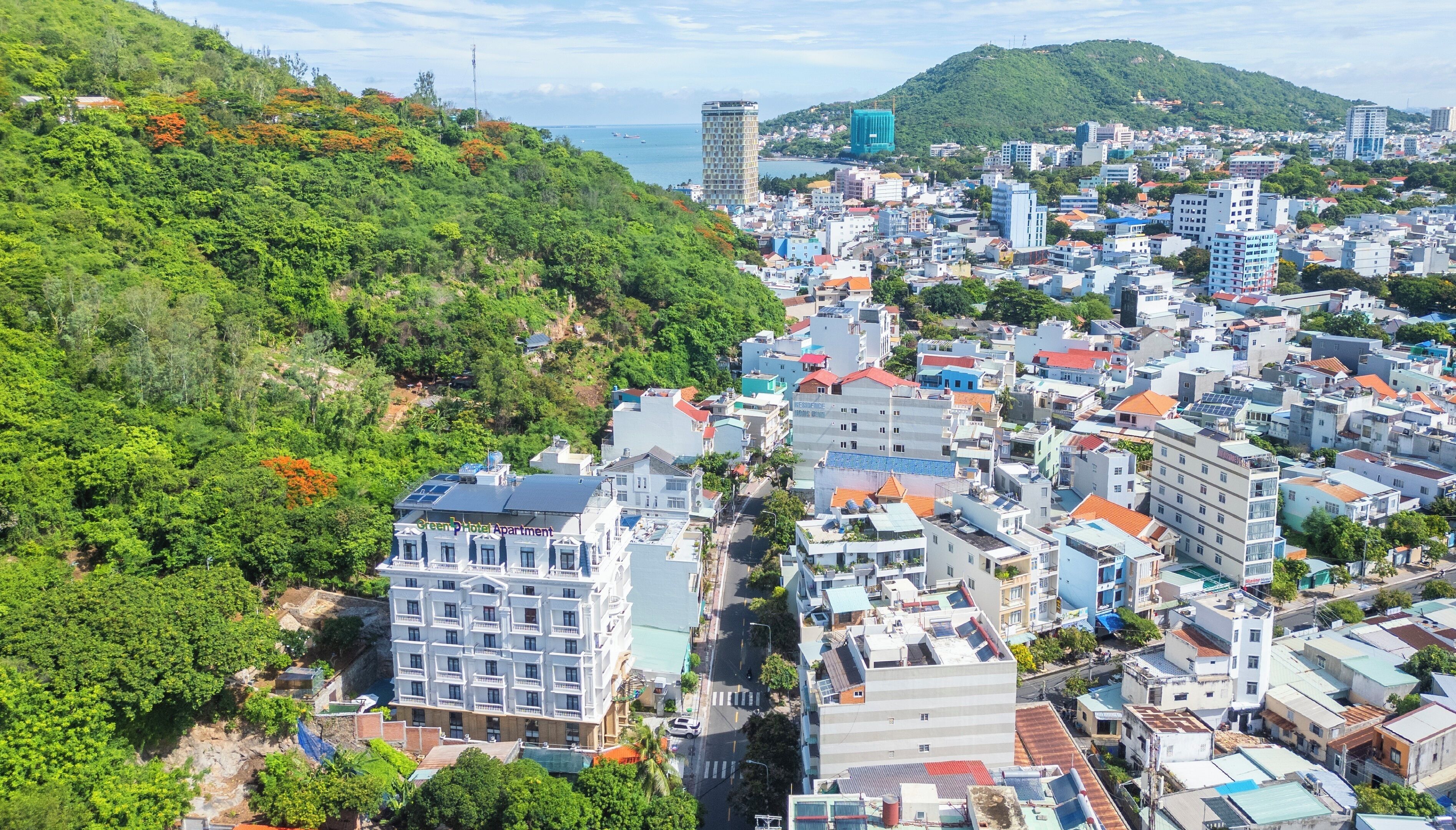 A hotel with multiple floors, a central courtyard, and a view of the surrounding cityscape and hills.