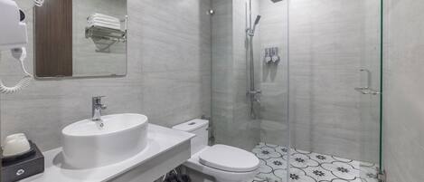 Et moderne badeværelse med vask, toilet og glasafskærmet brusekabine.
