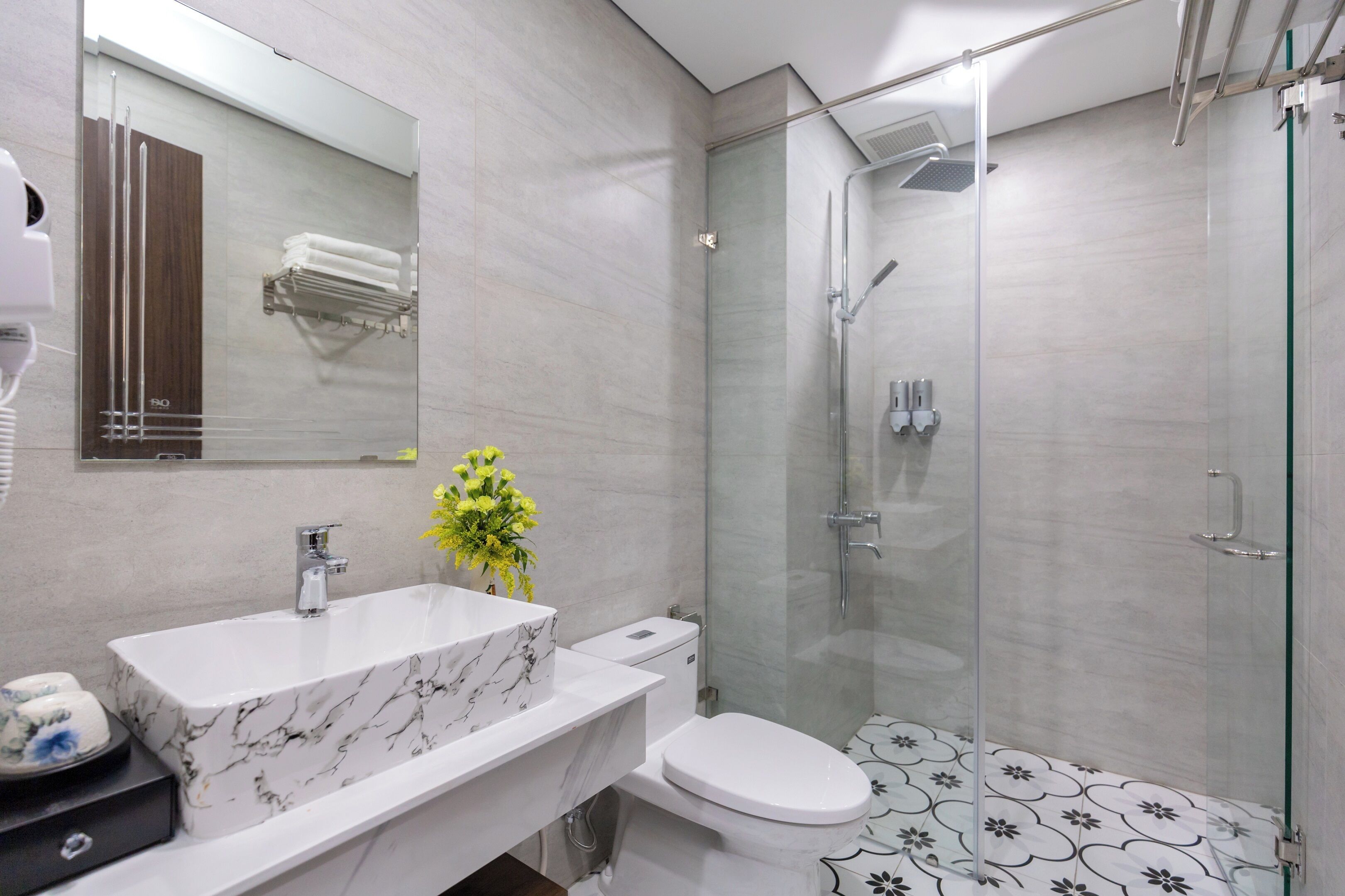 A modern bathroom with a marble sink, toilet, and glass-enclosed shower.