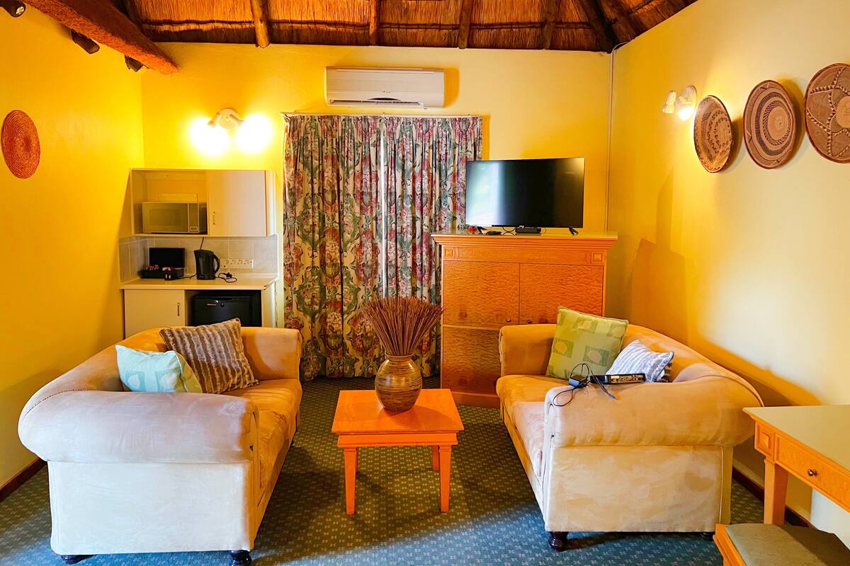 A living room with two sofas, a coffee table, a TV, a microwave, and a cabinet.