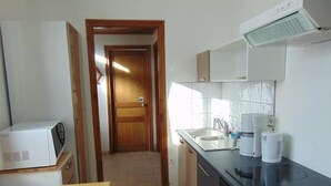 A compact kitchen with a microwave, sink, coffee maker, and stove.