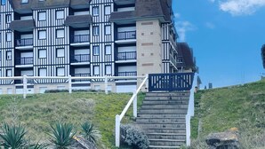 Un immeuble moderne à plusieurs étages, doté d’une façade de style traditionnel, d’un escalier menant à l’entrée et d’un chemin d’accès à l’avant.