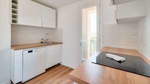 A modern kitchen with white cabinets, a dishwasher, and a wooden countertop. - Splendide T3 au Coeur de Marseille (Marseille)