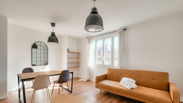 A modern living room with a wooden dining table, two chairs, a sofa, and a large window with curtains. - Splendide T3 au Coeur de Marseille (Marseille)