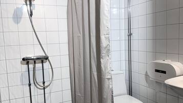 A modern bathroom with a shower, toilet, and a hand dryer.