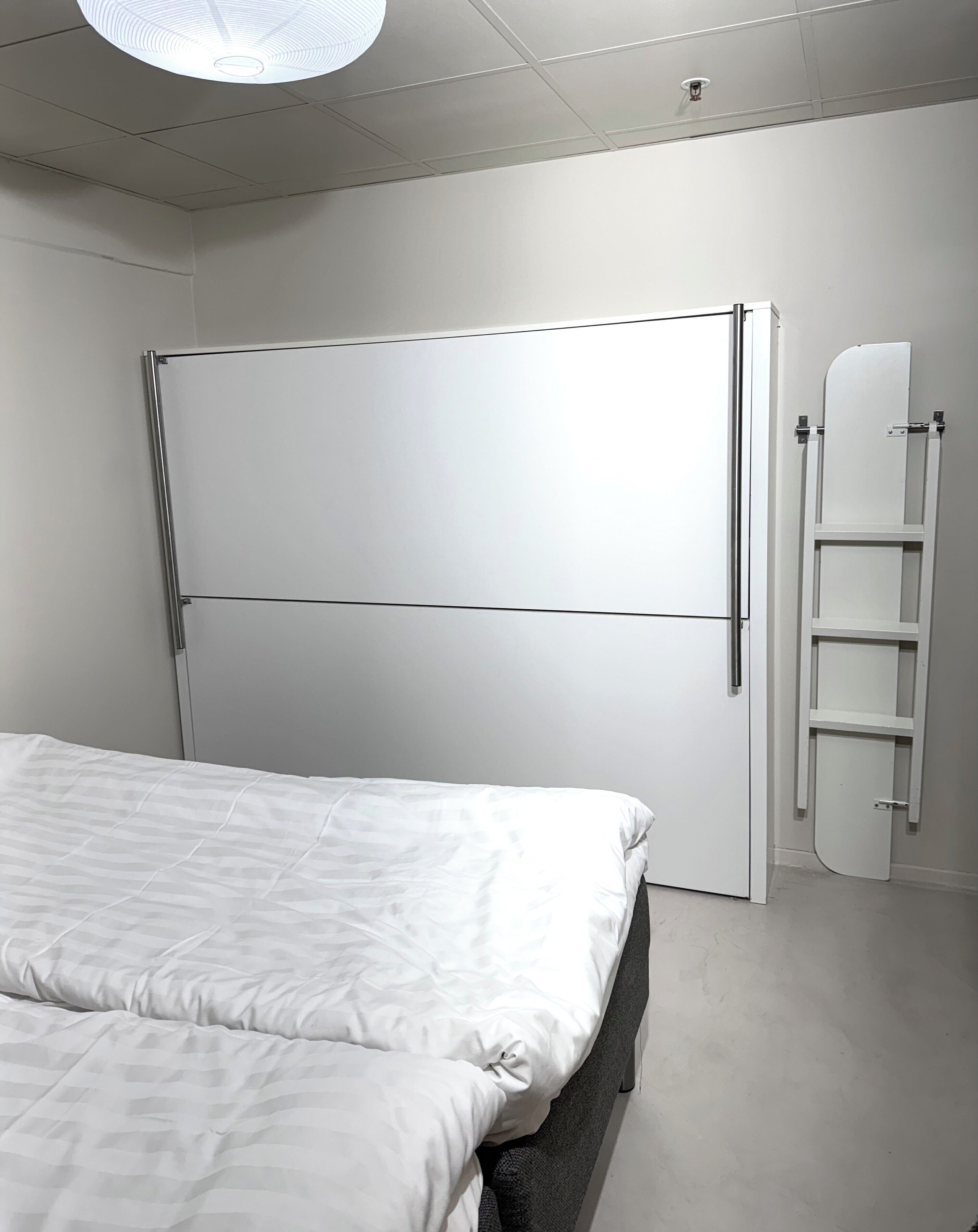 Un dormitorio con cama, armario y escalera empotrada.