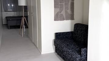 Una sala moderna con un sofá estampado, una lámpara y vistas a la cocina.
