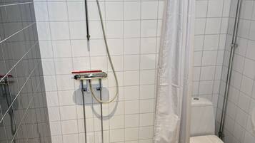 Ett modernt badrum med dusch, toalett och ett kaklat golv.