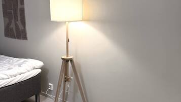 A modern bedroom with a single bed, a floor lamp, and a wall-mounted artwork.