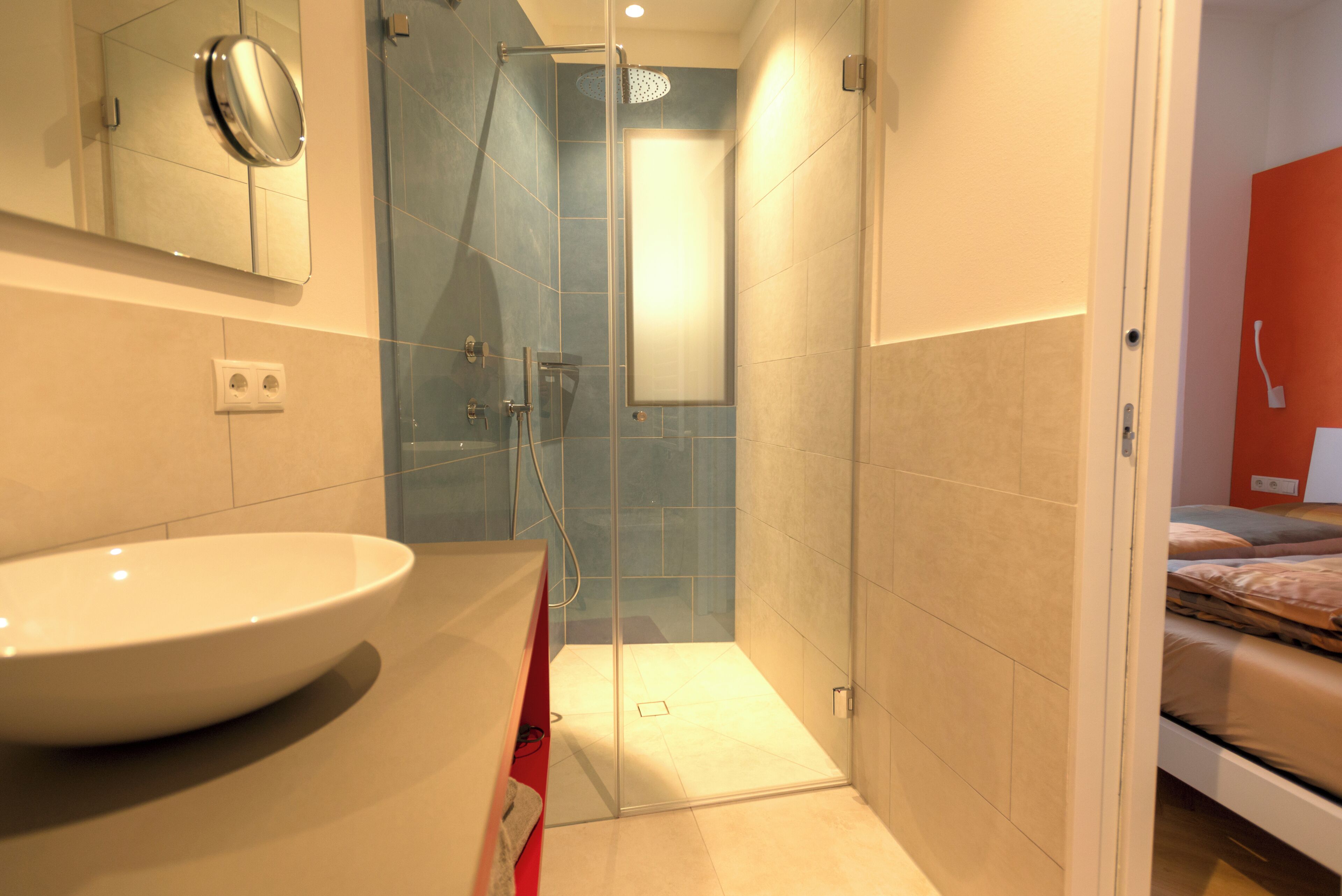 A bathroom with a large sink, a shower, and a mirror.
