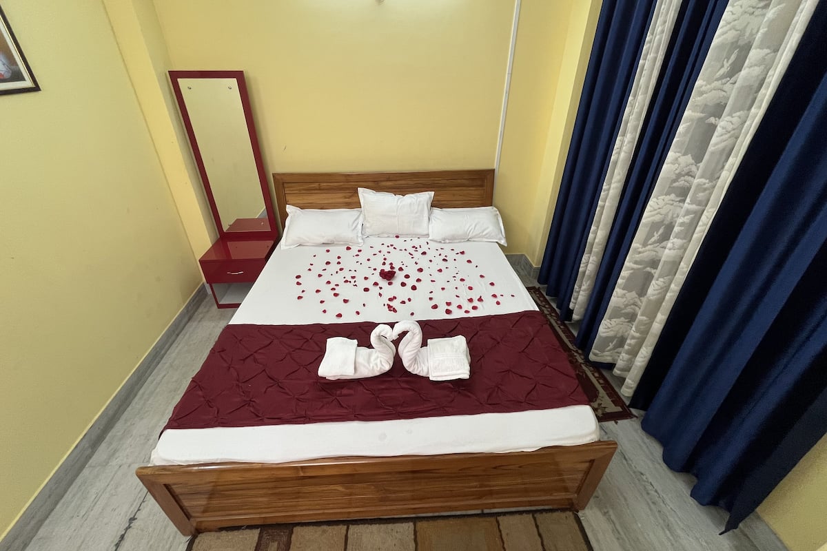 A neatly made bed with a red and white bedspread, white pillows, and a wooden headboard.