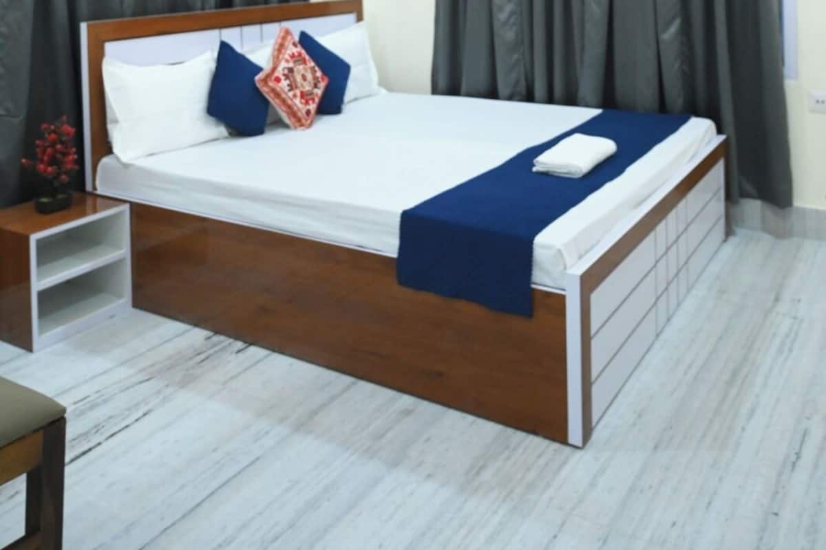 A modern hotel room with a wooden bed frame, a ceiling fan, and an air conditioning unit.