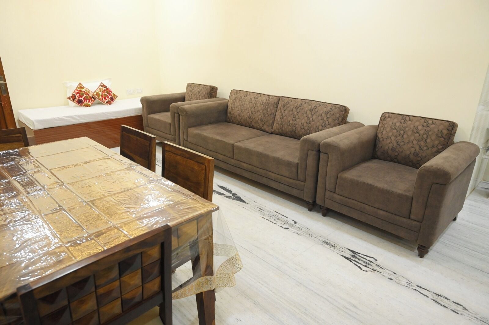 Una sala de estar con un conjunto de sofás, una mesa de comedor con sillas y un tapete estampado.