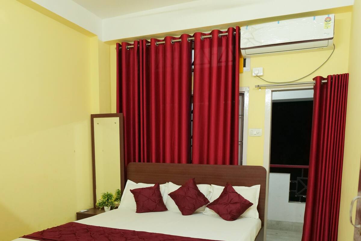 A bedroom with a bed, red curtains, a ceiling fan, and a window with curtains.