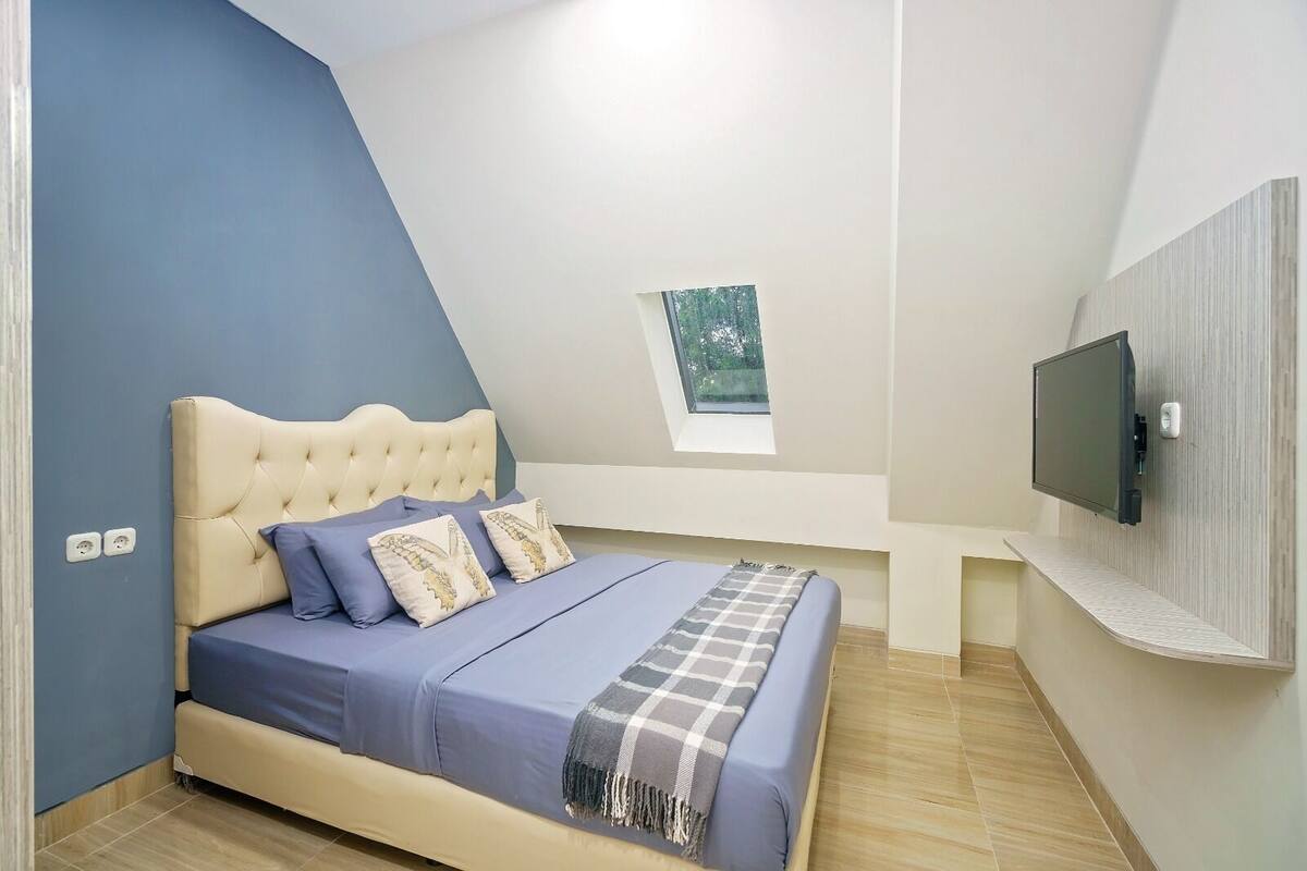 A bedroom with a bed, a window, and a TV.