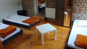 Ein Zimmer mit zwei Betten, einem kleinen weißen Tisch und einer Backsteinwand.