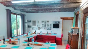 Ein Essbereich mit roten Stühlen und Tischen, einem Holzkabinett und einer Wand mit gerahmten Bildern.