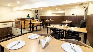 Ein Restaurant mit mehreren Tischen, jeweils gedeckt mit Tellern, Besteck und Servietten.