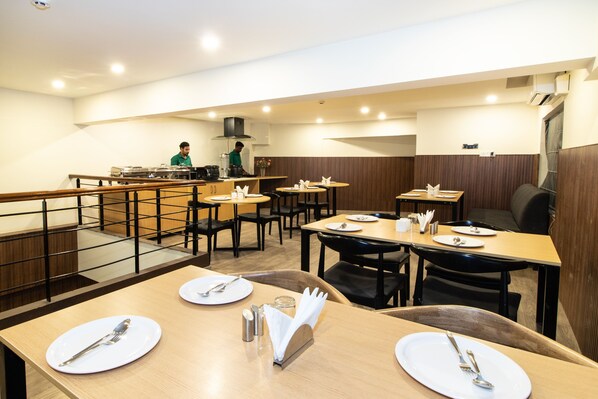 A restaurant with multiple tables, each set with plates, cutlery, and napkins.
