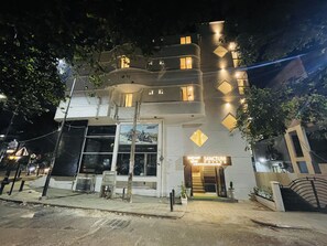 A multi-story hotel with a modern design, featuring a prominent entrance with a staircase and a sign for 'Sanctum Suites'.