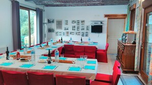 Un comedor con sillas tapizadas en rojo y mesas, techo de ladrillo y pared decorada con cuadros.