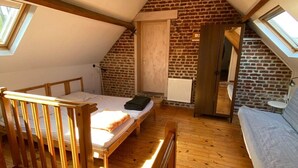 Dormitorio tipo loft con techo inclinado, piso de madera, cama, sofá y radiador.