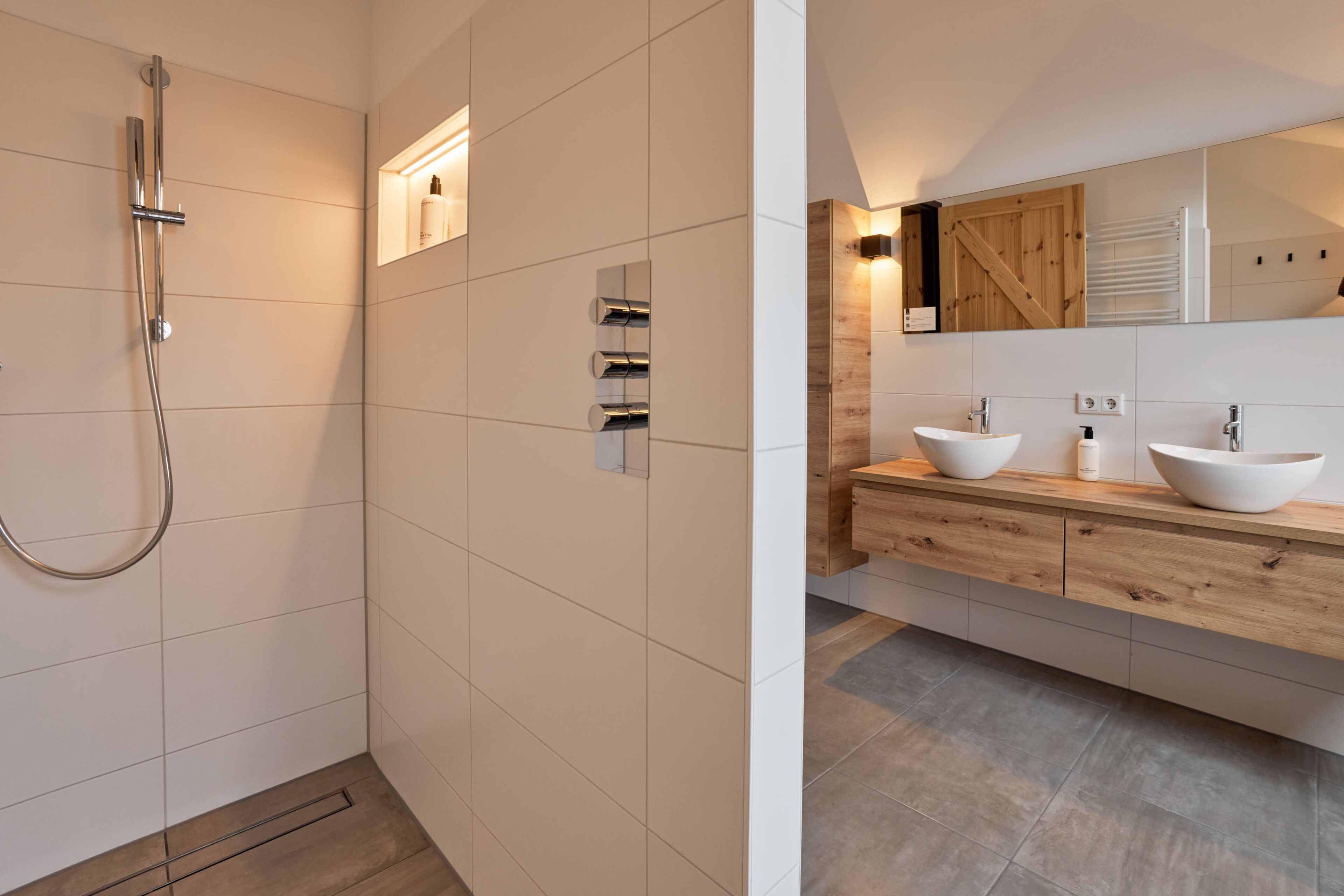 Une salle de bain moderne avec une douche, deux lavabos et un meuble-lavabo en bois.