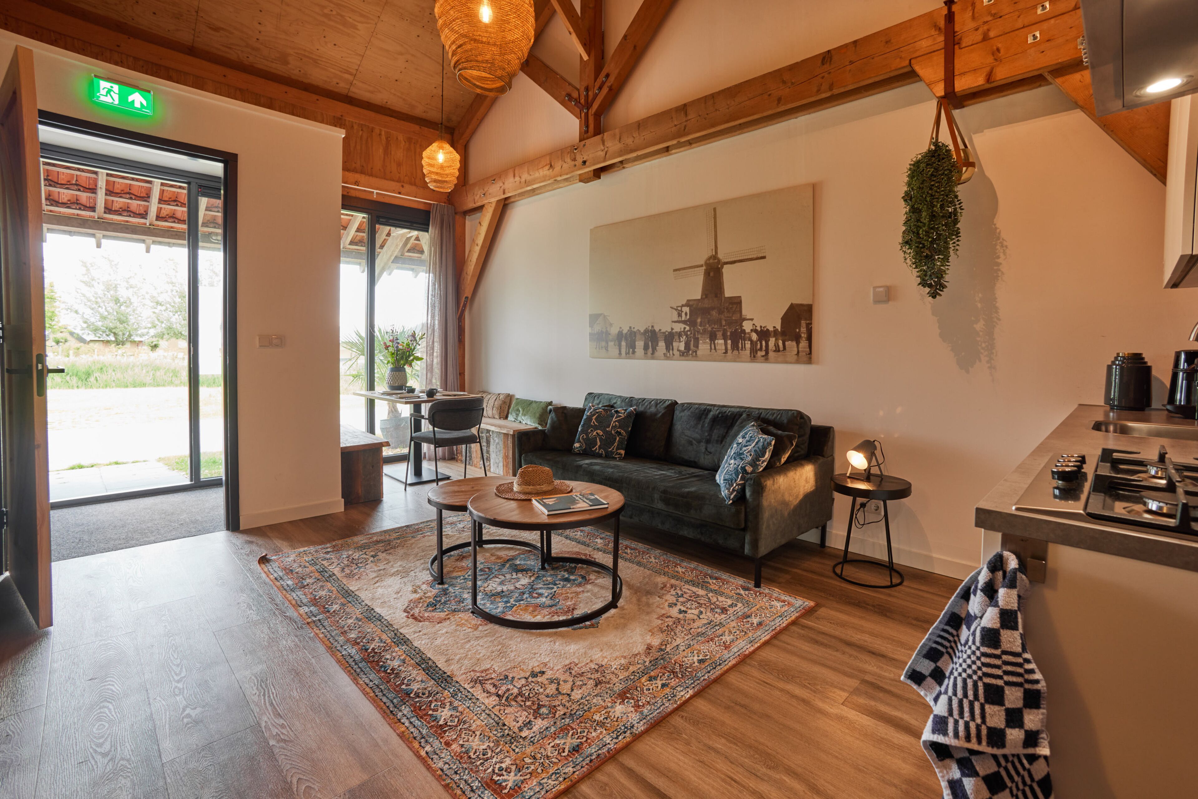 Een knus interieur met een houten plafond, een bank, een bijzettafeltje en een vloerkleed.