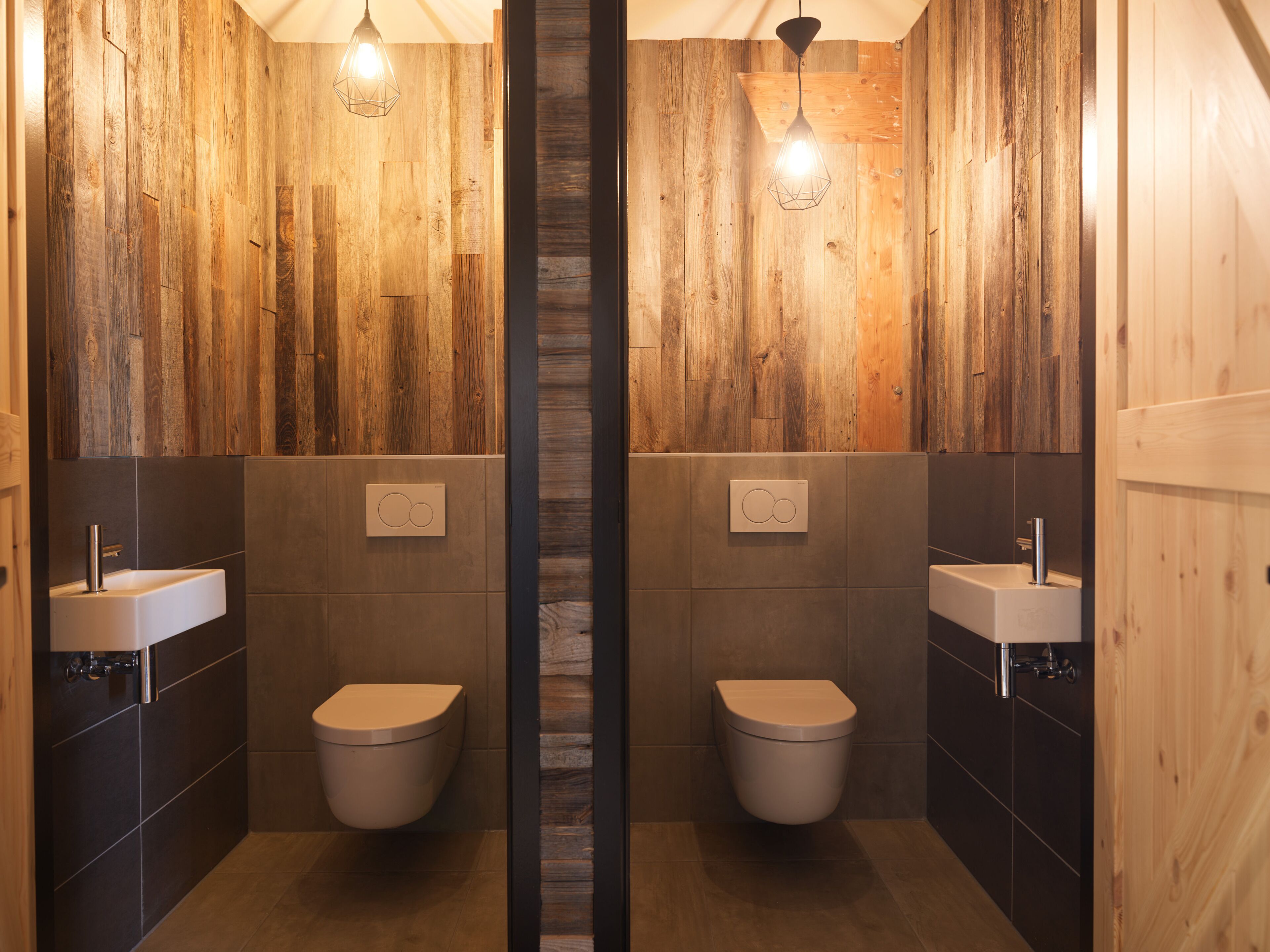 Une salle de bain avec des murs en bois, deux lavabos et deux toilettes.