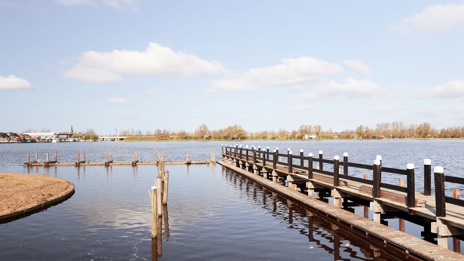 A wooden pier extending into a calm body of water with a clear sky above.